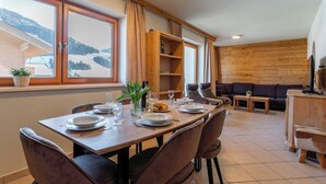 A dining area with a table set for four, a sofa, and a TV stand. - Superb apartment on the slopes with terrace (Hinterglemm)