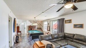 Un vaste salon doté d’une table de billard, d’un canapé en cuir et d’un ventilateur de plafond.