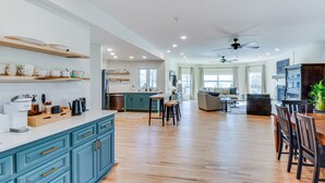 Una cocina amplia con armarios color turquesa, una mesa de comedor de madera y una zona de bar.
