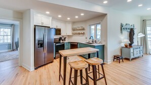 Una cocina amplia con refrigerador de acero inoxidable, taburetes de bar de madera y una pared de acento en azul claro.