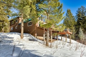 A wooden cabin with a deck, surrounded by snow and trees. - Wyoming Cabin w/ Hot Tub & Mountain-View Deck (Star Valley Ranch)