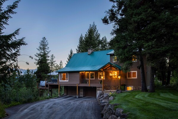 A log cabin with a green roof, multiple windows, and a garage. - Wyoming Cabin w/ Hot Tub & Mountain-View Deck (Star Valley Ranch)