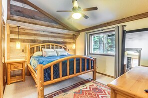 A wooden bed with a headboard, a nightstand, and a window with a view of trees. - Wyoming Cabin w/ Hot Tub & Mountain-View Deck (Star Valley Ranch)