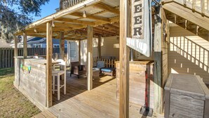 A wooden deck with a bar area, outdoor seating, and a staircase leading to an upper level. - Inviting Savannah Vacation Rental w/ Game Room! (Savannah)