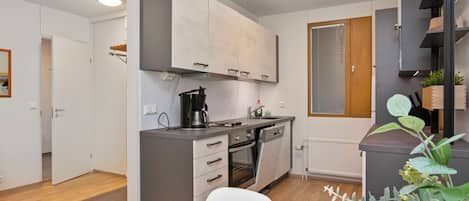 Una cucina moderna con mobili grigi, forno integrato e una finestra con persiane.