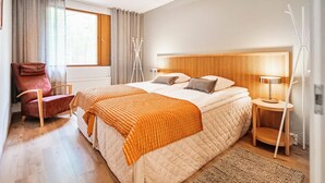 A modern hotel room with a large bed, a chair, a bedside table, and a lamp. - Mäntyranta 1 by Interhome (Punkaharju)