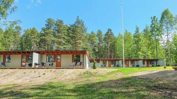 A row of cabins with outdoor seating, surrounded by a forested area.