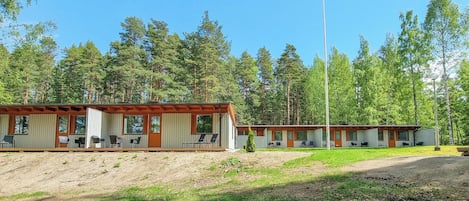 A row of cabins with outdoor seating, surrounded by a forested area.