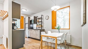 A modern kitchen with a dining area, wooden flooring, and a large window with a view. - Mäntyranta 1 by Interhome (Punkaharju)