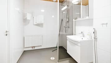 Une salle de bain moderne avec une douche à parois de verre, un lavabo blanc et un miroir au-dessus.