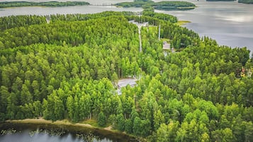 A forested area with a lake, a bridge, and a building with a flat roof.