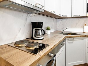 Uma cozinha moderna com bancada de madeira, cafeteira, pia e máquina de lavar louça.