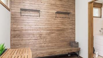 A room with a wooden wall, a bench, a radiator, and a basket.