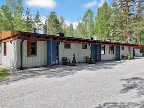 A row of cabins with individual doors, each with a small porch and a chair.