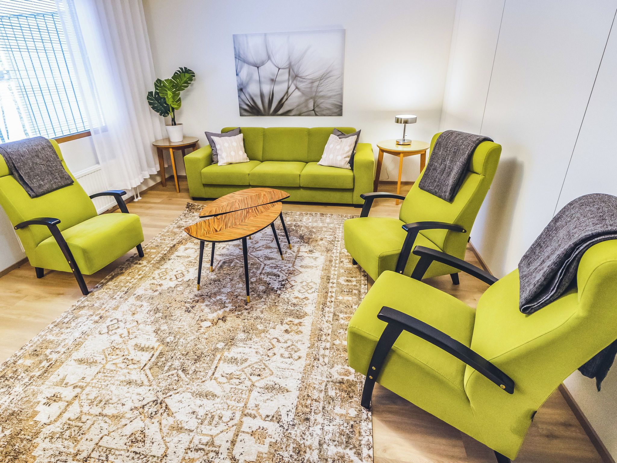 A living room with a green sofa, matching armchairs, a coffee table, and a patterned rug.