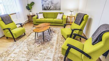A living room with a green sofa, matching armchairs, a coffee table, and a patterned rug.
