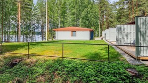 A cabin with a red roof, surrounded by a fenced yard and dense forest. - Mäntyranta 5 by Interhome (Punkaharju)