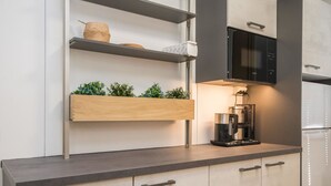 A modern kitchen with a built-in microwave, coffee maker, and wooden shelves with plants. - Mäntyranta 5 by Interhome (Punkaharju)