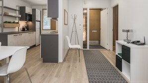 A modern kitchen with a central island, white cabinetry, and a dining area with a white table and chairs. - Mäntyranta 5 by Interhome (Punkaharju)