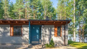 A cabin with a blue door, two windows with wooden shutters, and a gravel driveway. - Mäntyranta 5 by Interhome (Punkaharju)