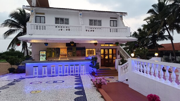 A two-story building with a bar area, outdoor seating, and a staircase leading to the entrance. - Qees Empire Beachfront Resort (Calangute)