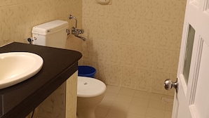 A bathroom with a toilet, sink, and shower. - Qees Empire Beachfront Resort (Calangute)