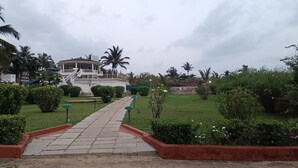 A pathway leading to a building with a covered porch and a staircase. - Qees Empire Beachfront Resort (Calangute)