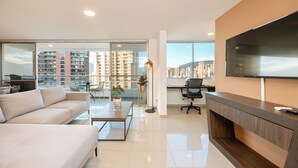 A modern living room with a sofa, coffee table, and a TV mounted on the wall.