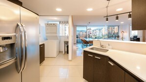 A modern kitchen with a stainless steel refrigerator, a built-in oven, and a large window offering a city view.