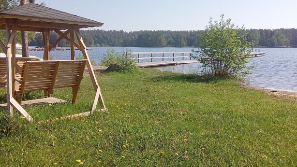 Un belvédère avec des bancs donnant sur un lac, une jetée s’avançant dans l’eau et une rive bordée d’arbres.