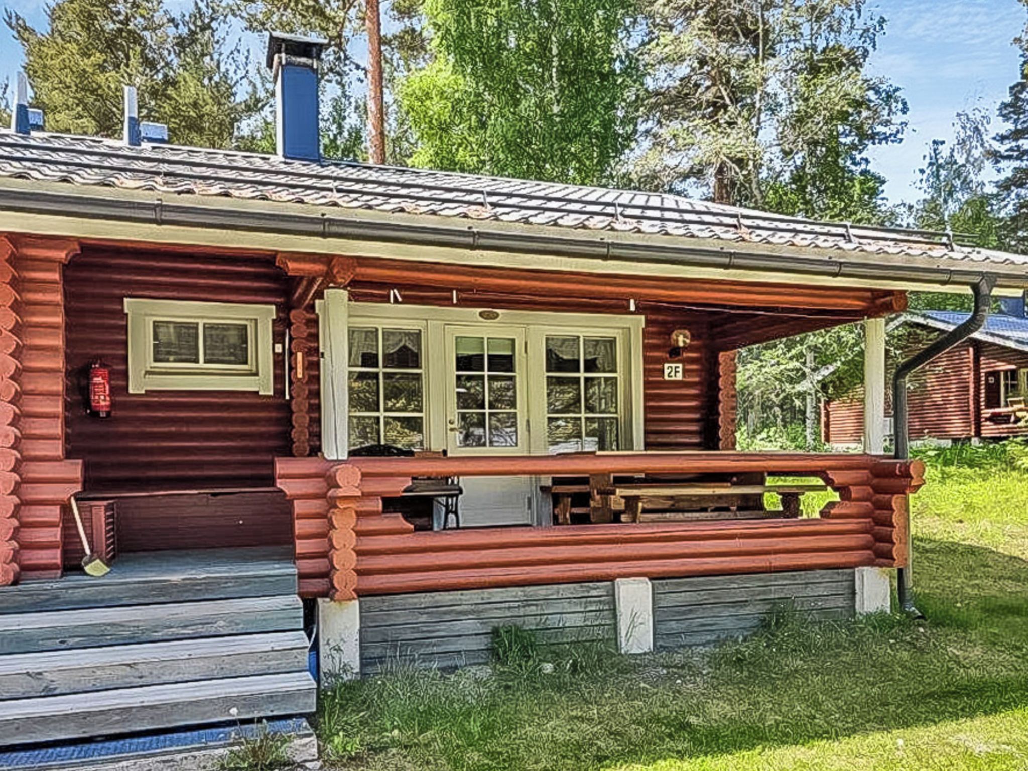 Eine Blockhütte mit Veranda, Schornstein und Fenster.
