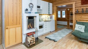 L’intérieur d’un chalet confortable, avec une cheminée, des meubles blancs, un coin cuisine et un canapé vert.