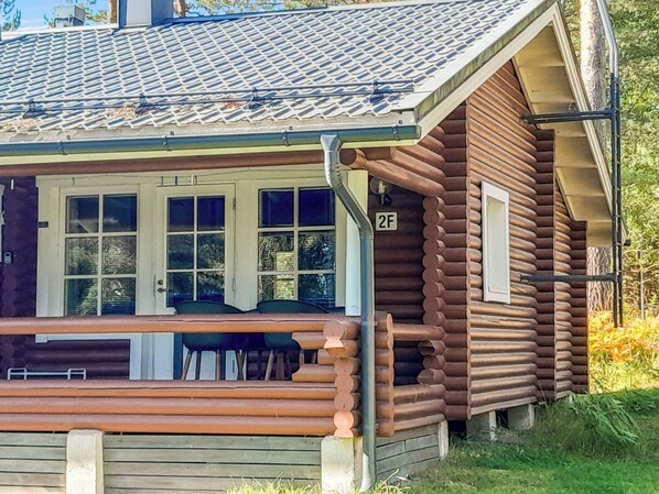 Une cabane en rondins avec un porche, une plaque portant le numéro « 2F » et une fenêtre donnant sur les environs.