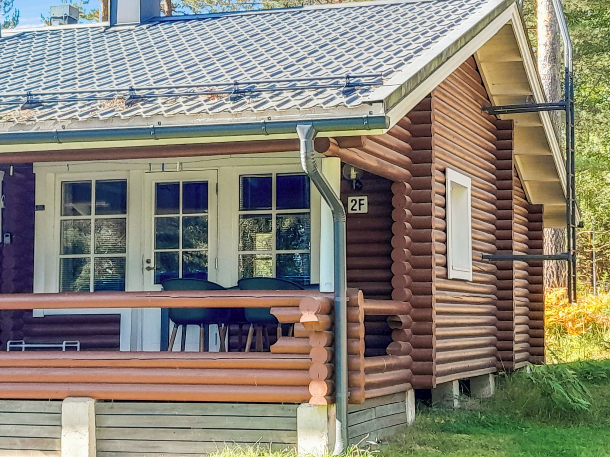 A log cabin with a porch, a number '2F' sign, and a window with a view of the surrounding area.