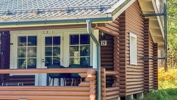 A log cabin with a porch, a number '2F' sign, and a window with a view of the surrounding area.