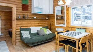 L’intérieur d’un chalet confortable, avec un canapé, une table à manger et un jeu d’échecs.