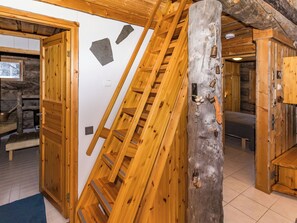 A wooden interior with a wooden staircase, a wooden door, and a stone wall.