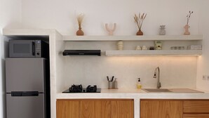 A modern kitchen with a stainless steel refrigerator, a gas stove, wooden cabinets, and a white countertop.