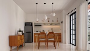 A modern kitchen with a central island, wooden chairs, and pendant lights.