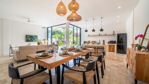 A modern kitchen with a dining area, featuring a wooden table, woven chairs, and pendant lighting. - Private Pool | Rooftop Views | Canggu Base (Canggu)
