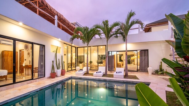 A modern poolside area with glass doors, lounge chairs, and potted plants. - Private Pool | Rooftop Views | Canggu Base (Canggu)
