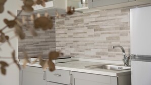 A modern kitchen with a tiled backsplash, stainless steel sink, and white cabinetry. - Splendid Two-room Apartment in Ostuni Renovated and Full Comfort (Ostuni)