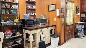 Una cocina con paredes de madera, microondas, lavamanos y cubo de basura.
