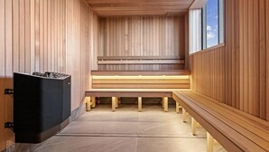 Un sauna avec des bancs en bois et un appareil de chauffage noir.