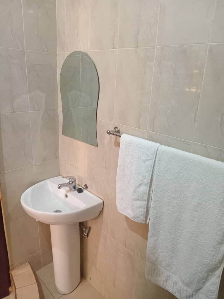 Ein Badezimmer mit einem weißen Waschbecken, einem Spiegel und einem Handtuch an einem Halter.