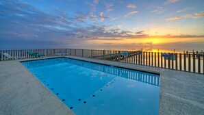 A rectangular swimming pool with a wooden deck and a white fence. - 6BDR, Balcony w/ Bay View, Shared Pool + Boat Dock | Keeper Red by AvantStay (Corpus Christi)