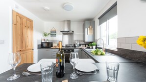 A modern kitchen with a dining area set for a meal. - Wheal Prosper Lodge (Helston)