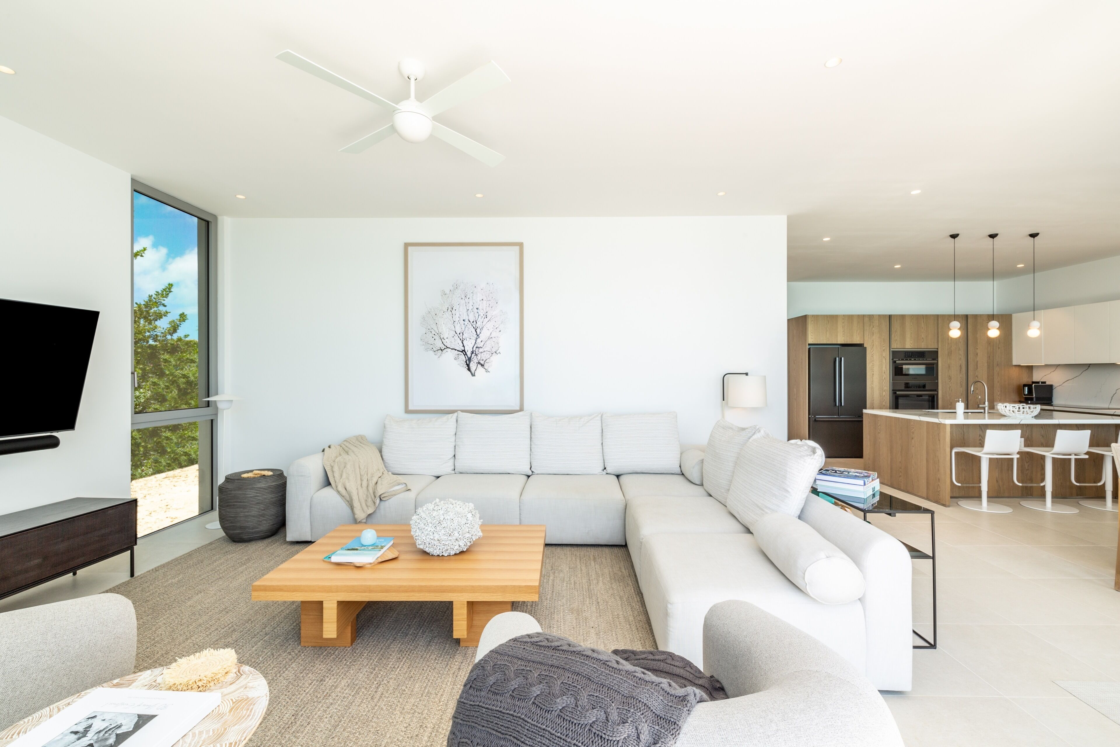 A modern living room with a sectional sofa, a coffee table, and a flat-screen TV.