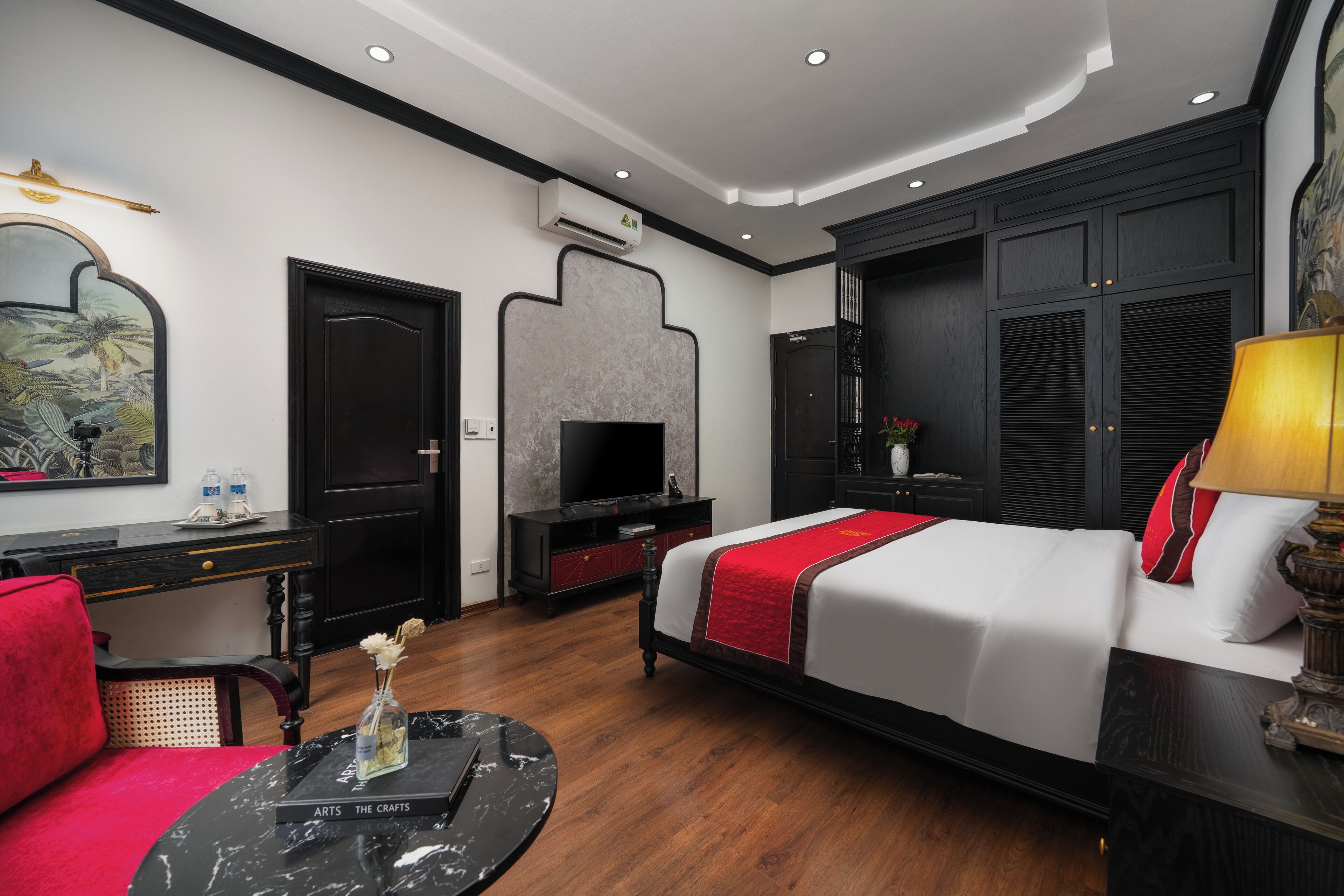 A hotel room with a bed, a desk, a television, and a wall-mounted air conditioning unit.