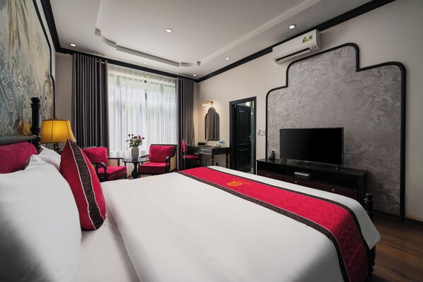A hotel room with a large bed, a TV, a desk, and a chair.